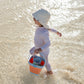 Lifestyle image of a toddler running on the seashore, wearing a MIKOU full coverage UV baby swimsuit